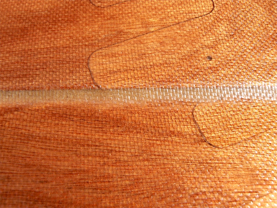 Voici un gros plan de la stratification au niveau du joint digital de l'arrière. On voit encore très bien la trame du tissu, mais elle disparaitra quand j'aurai ajouté une couche ou deux d'époxy. Le point est un trou de suture bouché. On ne voit pas son jumeau qui est sous le joint entre les bordés. 